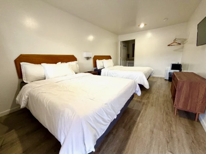 Room with two beds, a dresser and a mini fridge